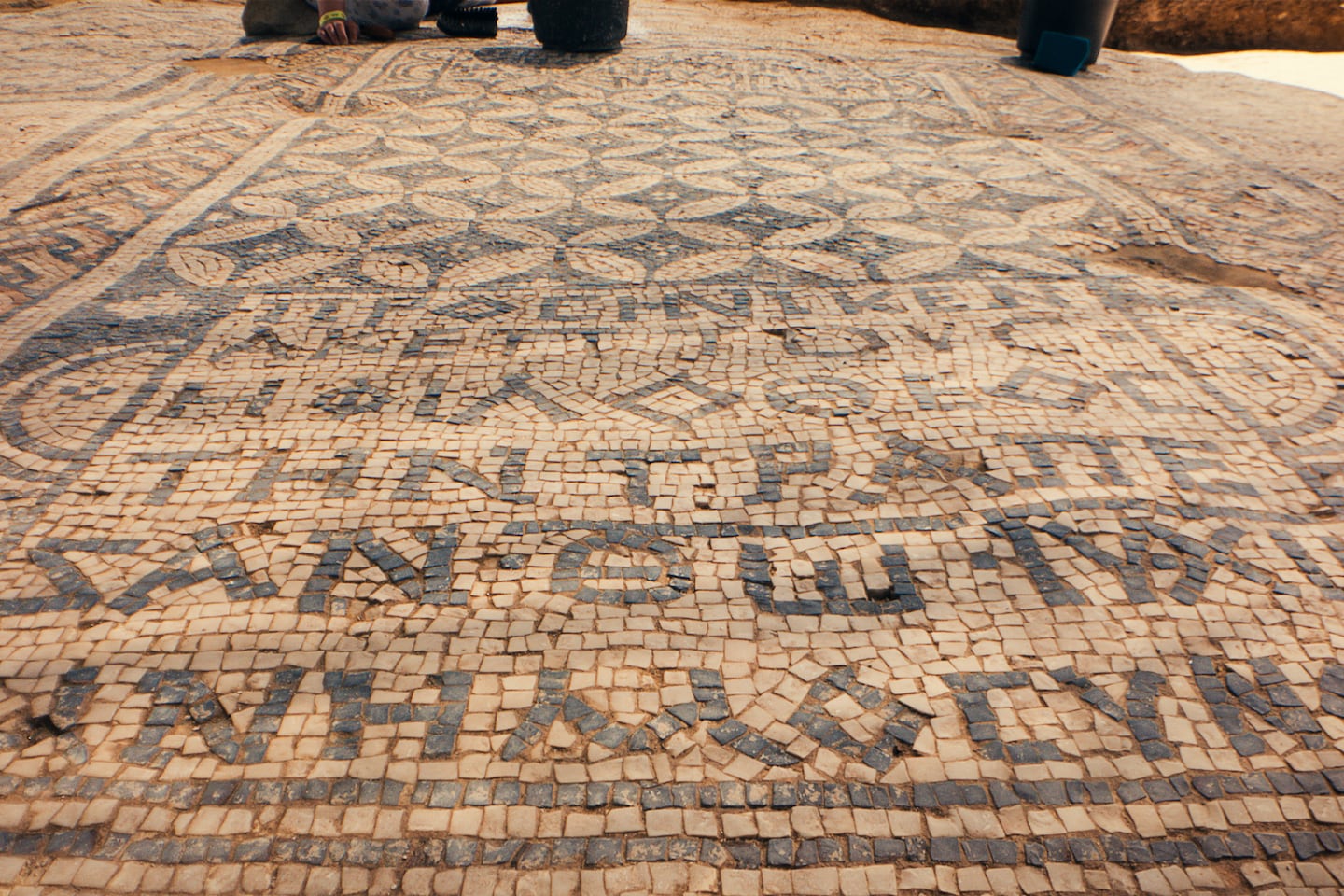 En inskription på grekiska i Megiddo-mosaiken med orden “till minne av Gud Jesus Kristus” på andra raden uppifrån.