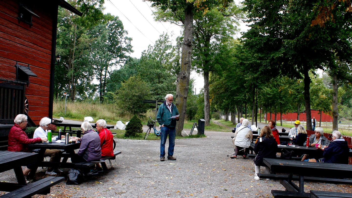 Medlemmar i RPG Järfälla sitter vid utebord. I mitten står Urban Norstedt och pratar.