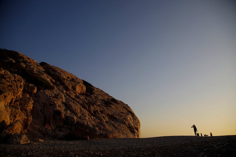 A woman walks by Aphrodite's Rock, 'Petra tou Romiou', the spot where according to ancient Greek mythology the ancient goddess Aphrodite was born, near Paphos, Cyprus, Monday, July 13, 2020. (AP Photo/Petros Karadjias)