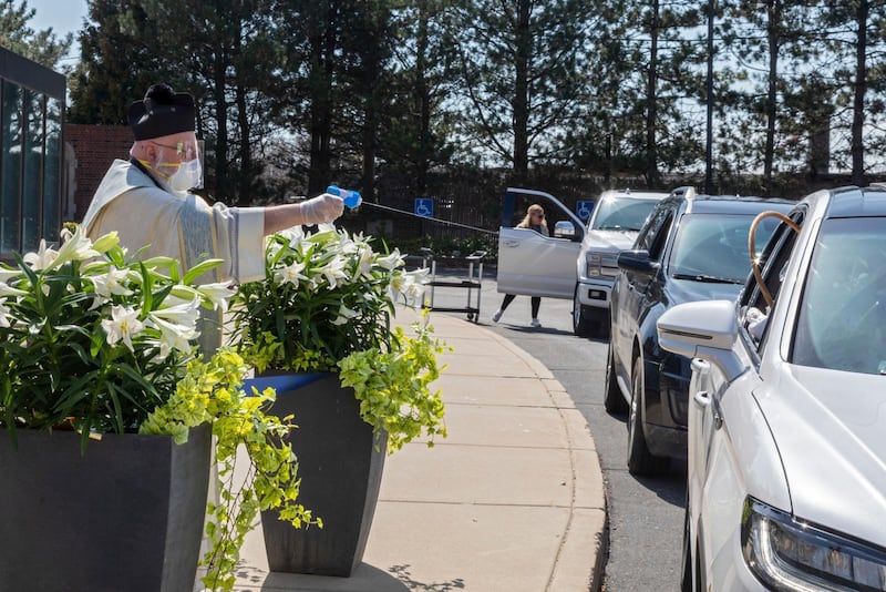 Timothy Pelc välsignar påskkorgar som passerande sträcker fram  utanför kyrkan St. Ambrose i Grosse Pointe Park.