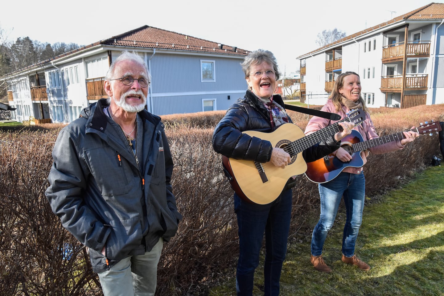 Bilder från Strömsnäsbruk till artikel om sång utanför äldreboenden. Helén Olsson och Anders Olsson samt Boel Dougan sjunger och spelar. På balkongen Göta Eriksson, 96 år. Samt ett antal glada icke namngivna pensionärer som lyssnar och sjunger med i sången. Corona. Coronavirus. Covid-19.