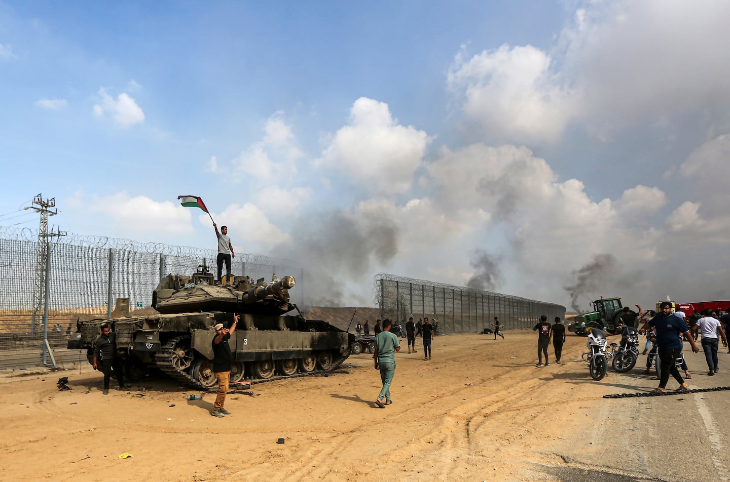 Palestinier viftar med flagga vid förstörd israelisk stridsvagn.